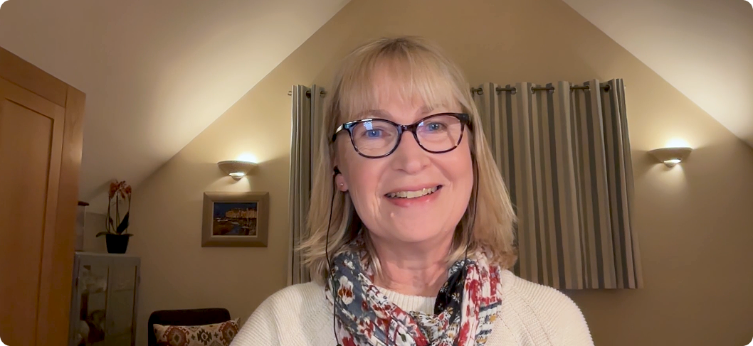 This is a link to a video. Helen White, an older white woman with shoulder-length blonde hair and wearing black glasses, is smiling at the viewer.