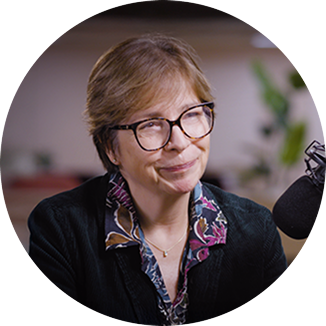 Professor Claire Harrison, an MPN specialist. She is an older woman with black glasses and short brown hair. She has a floral collar on her black top