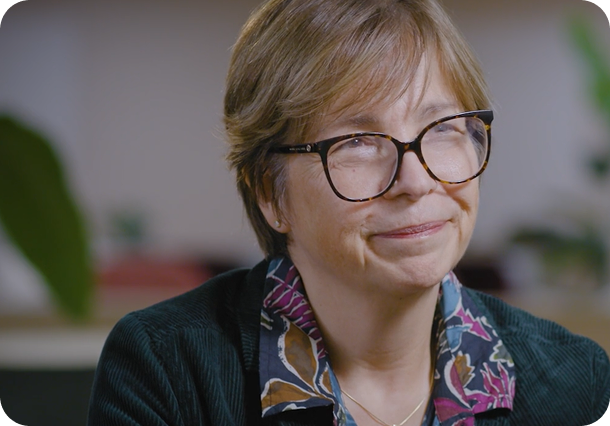 A link to a podcast. Professor Claire Harrison, an MPN specialist. She is an older woman with black glasses and short brown hair. She has a floral collar on her black top, and is looking off to the right.