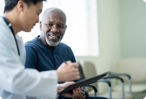 An older black man speaking with a young Asian doctor