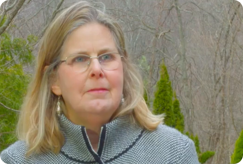 A link to a video. An older white woman named Chris with blonde hair and wearing a grey jacket is ready to speak.