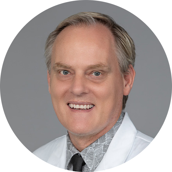 C. Ola Landgren, MD, PhD. An older man smiling at the viewer, wearing a white lab coat and a grey shirt and black tie. He has close cropped hair and is clean shaven.