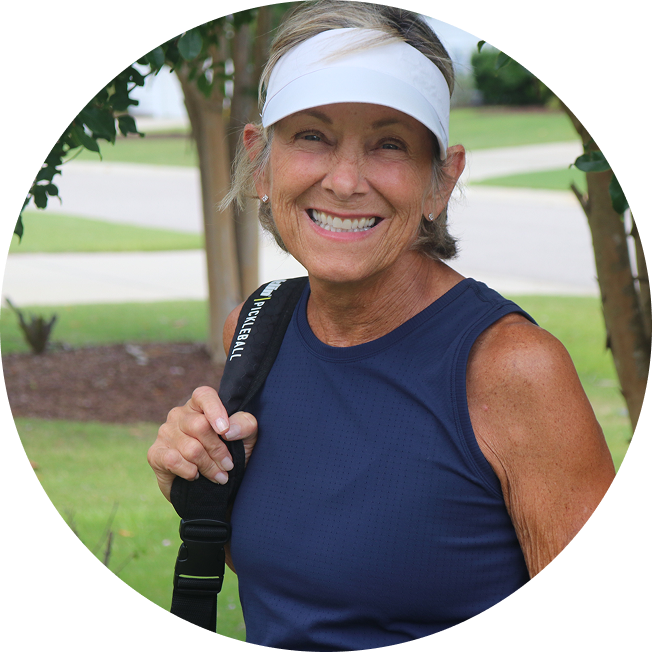 Karin, a person living with multiple myeloma. She is wearing a white visor and a blue tank top, and is carrying a black athletic bag.
