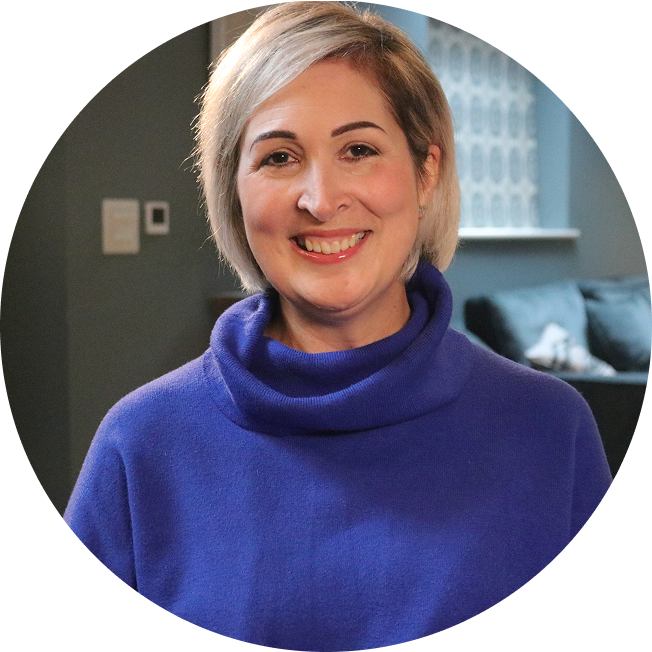Lou, a person living with multiple myeloma. She has a short blonde bob and is wearing an ultramarine blue top