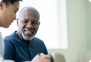An older black man speaking with a young Asian doctor